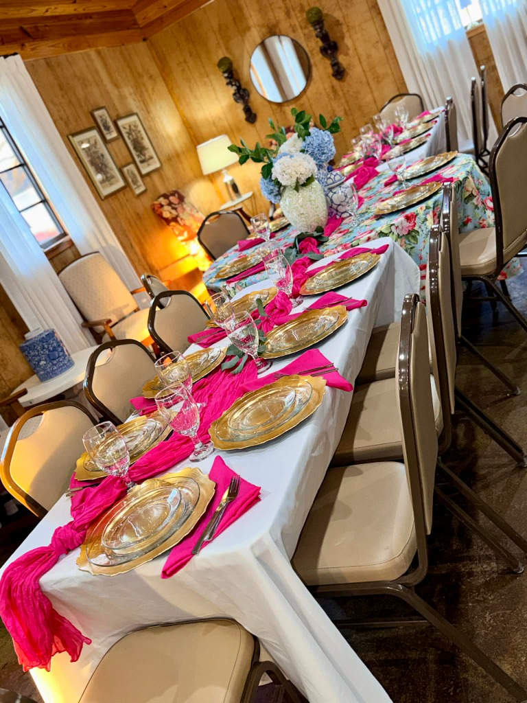 Elegant long table with gold chargers, hot pink napkins, and crystal glassware
