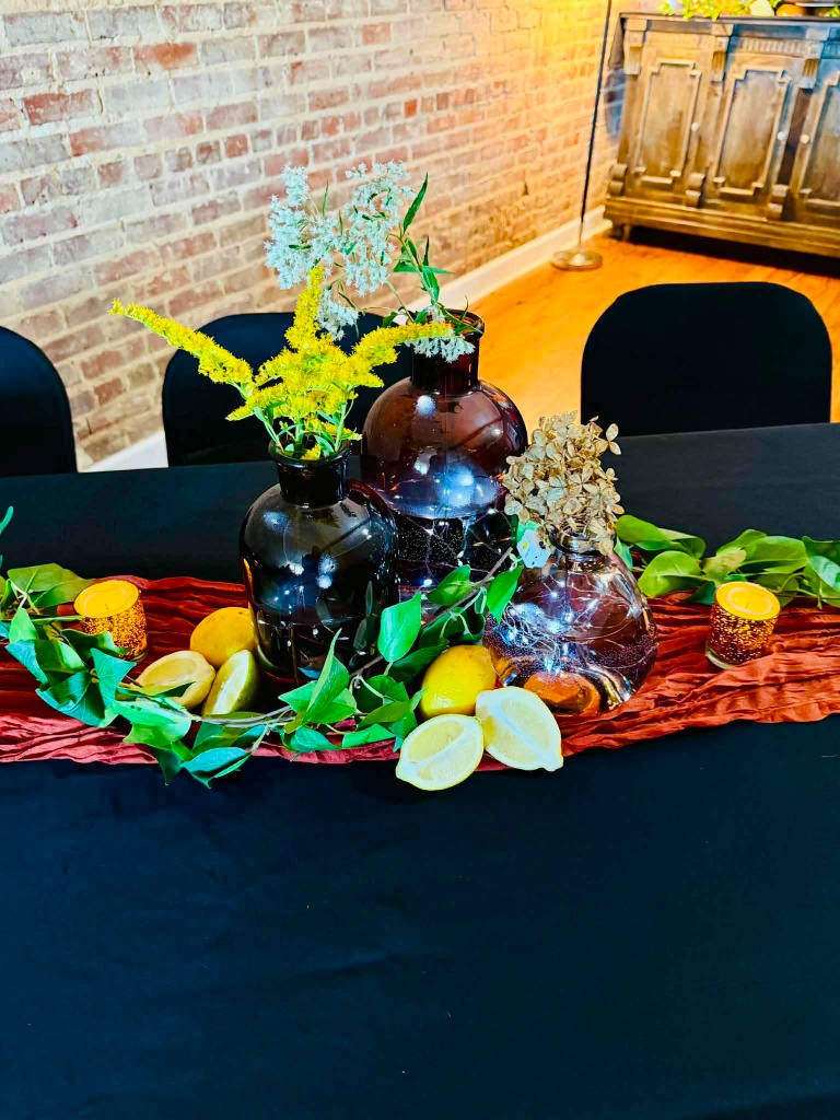 Rustic centerpiece with amber glass vases, fresh lemons, and string lights