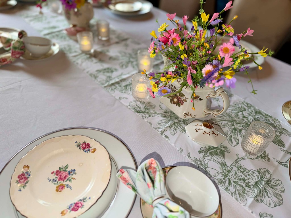 Elegant wedding shower table setting with vintage china, wildflowers, and candlelight